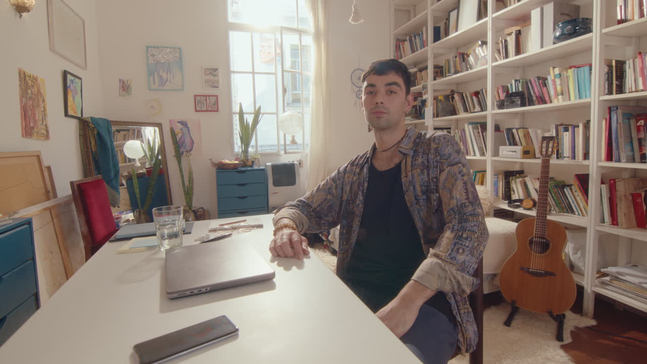 Young Man Posing on Camera at Desk with Laptop at Home