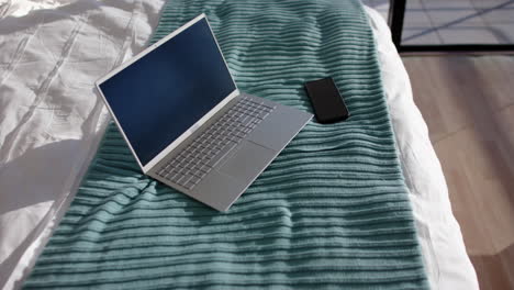 Laptop and smartphone on bed, ready for work or relaxation at home, copy space