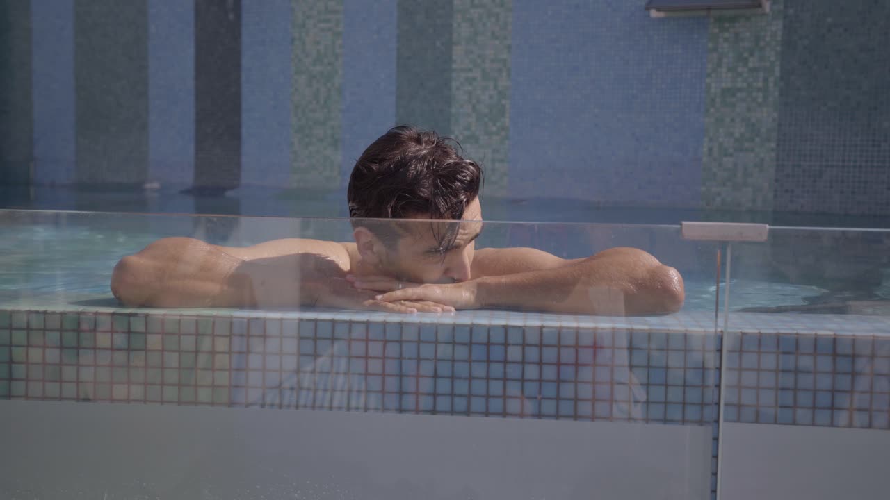 햇살 아래 고급스러운 수영장에서 휴식을 취하고 그 밖으로 기어오르는 청년