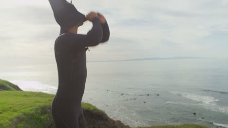 a surfer puts on his wetsuit at a remote surf spot