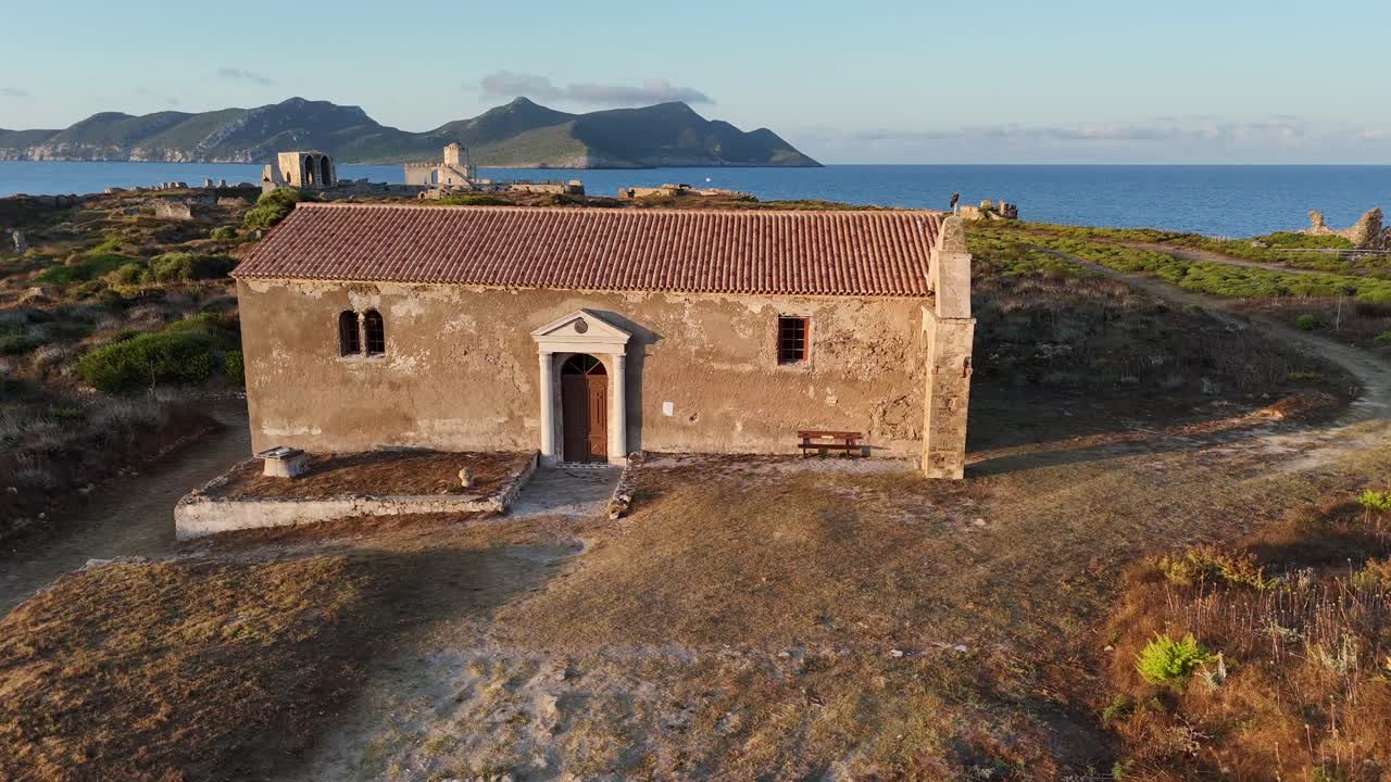 Methoni,Messenia,Peloponnese,Aerial view circle pan left around the church inside Methoni Castle during golden hour with clouds,hills and blue sea at the back ground