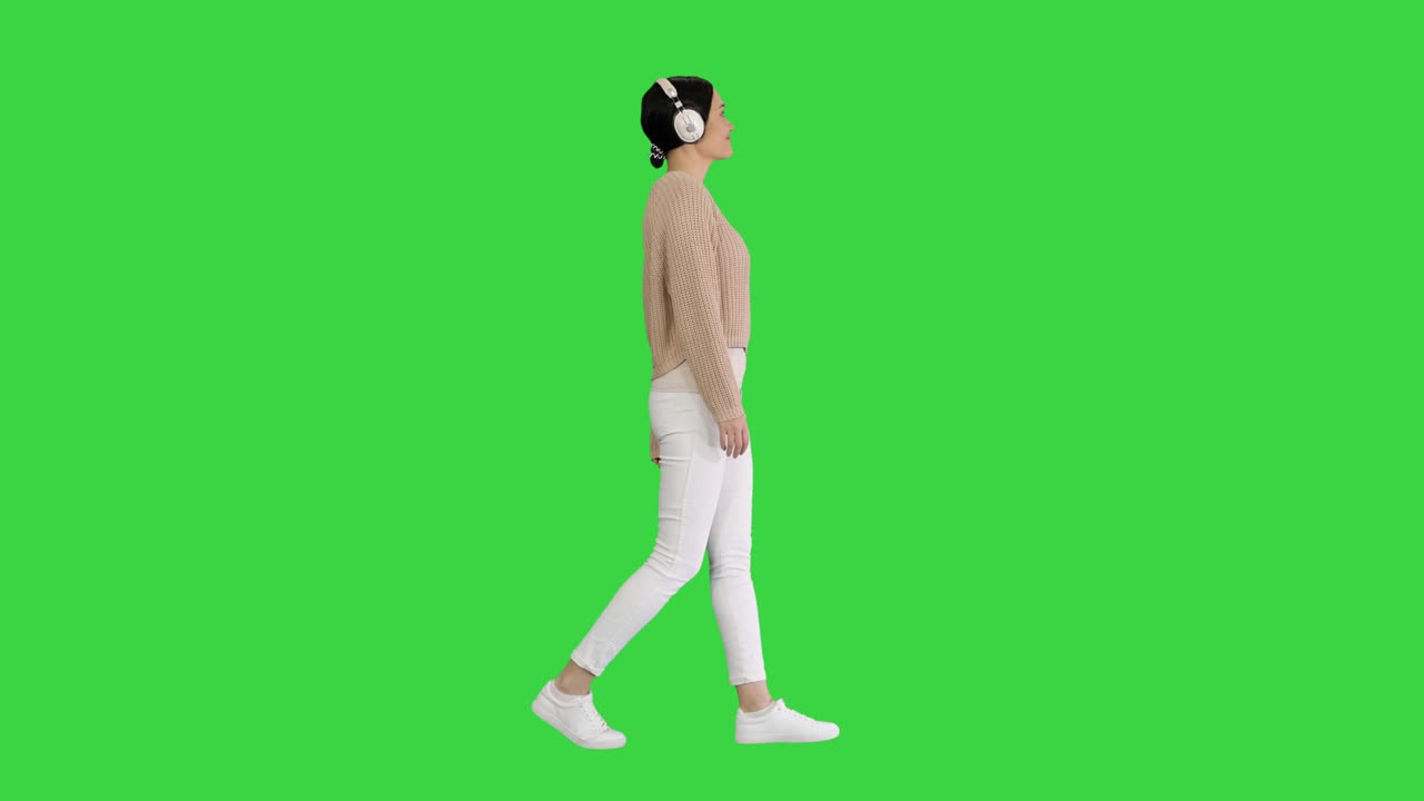 녹색 스크린, 크로마 키에서 음악을 듣는 헤드폰을 가진 젊은 여성