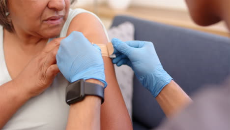 applying bandage, healthcare worker assists senior woman after school vaccination