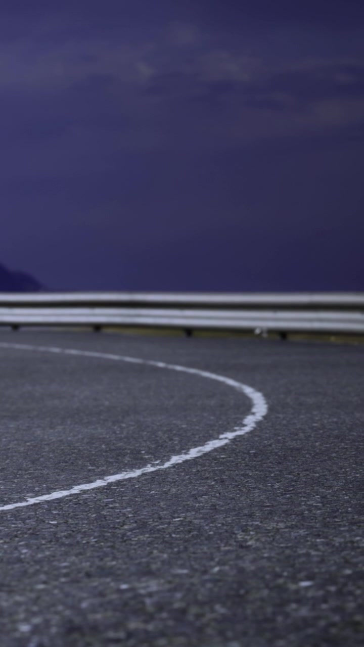 Curved road with white markings and mountain landscape during evening