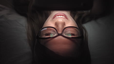 woman lying in bed, reading on tablet
