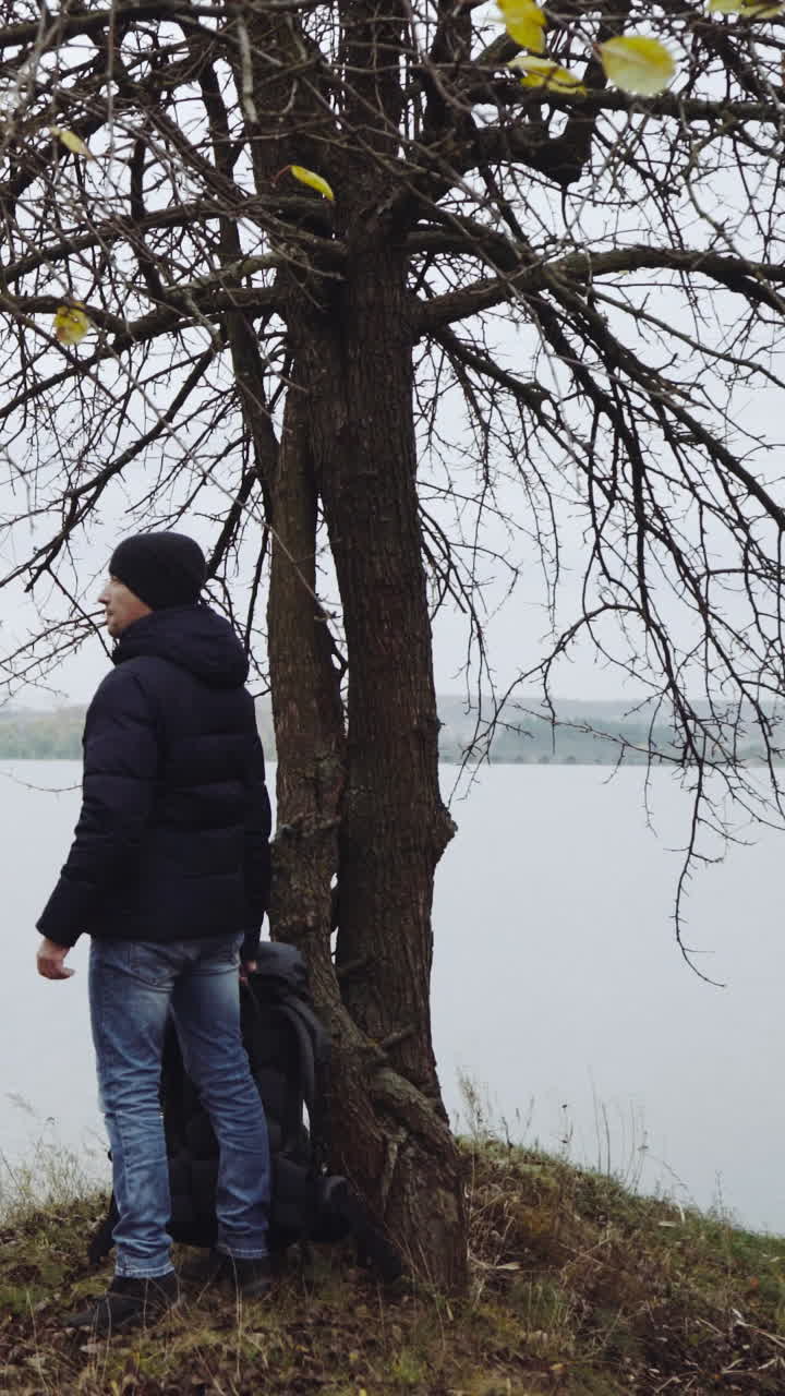 Uomo turista in piedi vicino al fiume. Vista posteriore di un uomo solitario in piedi con lo zaino vicino al fiume.