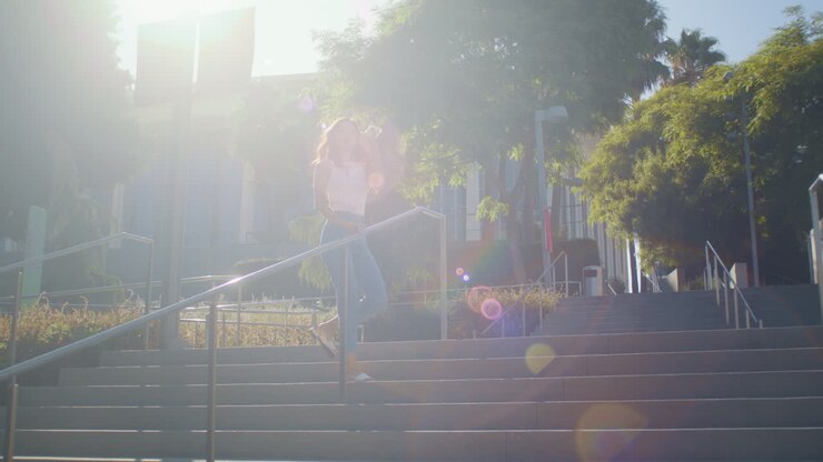 Mulher de cabelo comprido correndo escada acima para tirar foto. Jovem asiática subindo a escadaria para tirar uma selfie