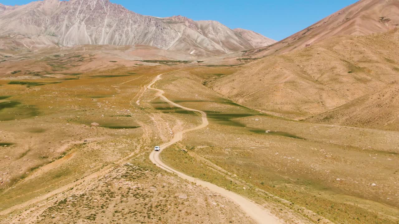 автомобиль едет по грунтовой дороге в сторону горы в солнечный день в узбекистане