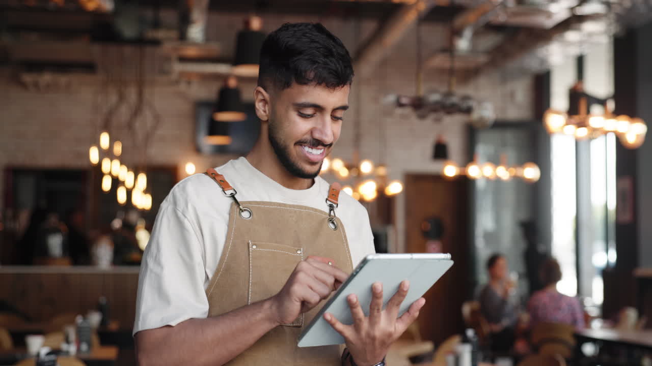 Smilende tjener bruger digital tablet på en moderne café