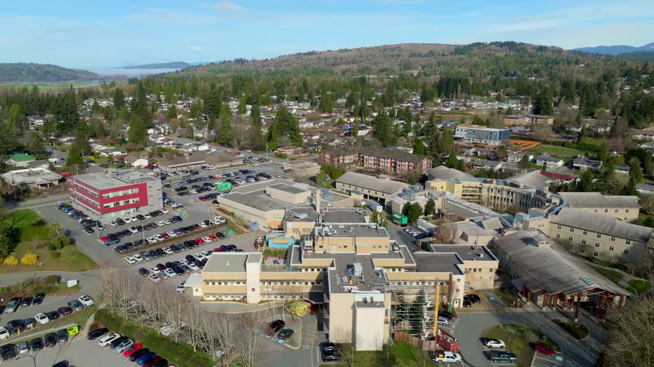 Mission Memorial Hospital Buildings With Parking Lots And Surrounding Residential Neighborhoods In Mission, BC, Canada. aerial pullback shot