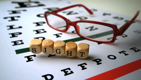 dice spelling out sight falling onto eye test next to glasses