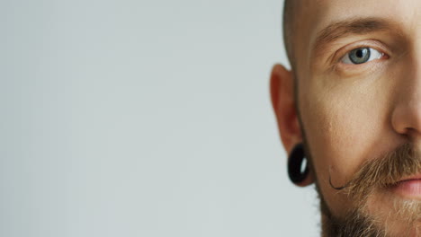 close up of the attractive male hipster half face with earings smiling and looking at the camera