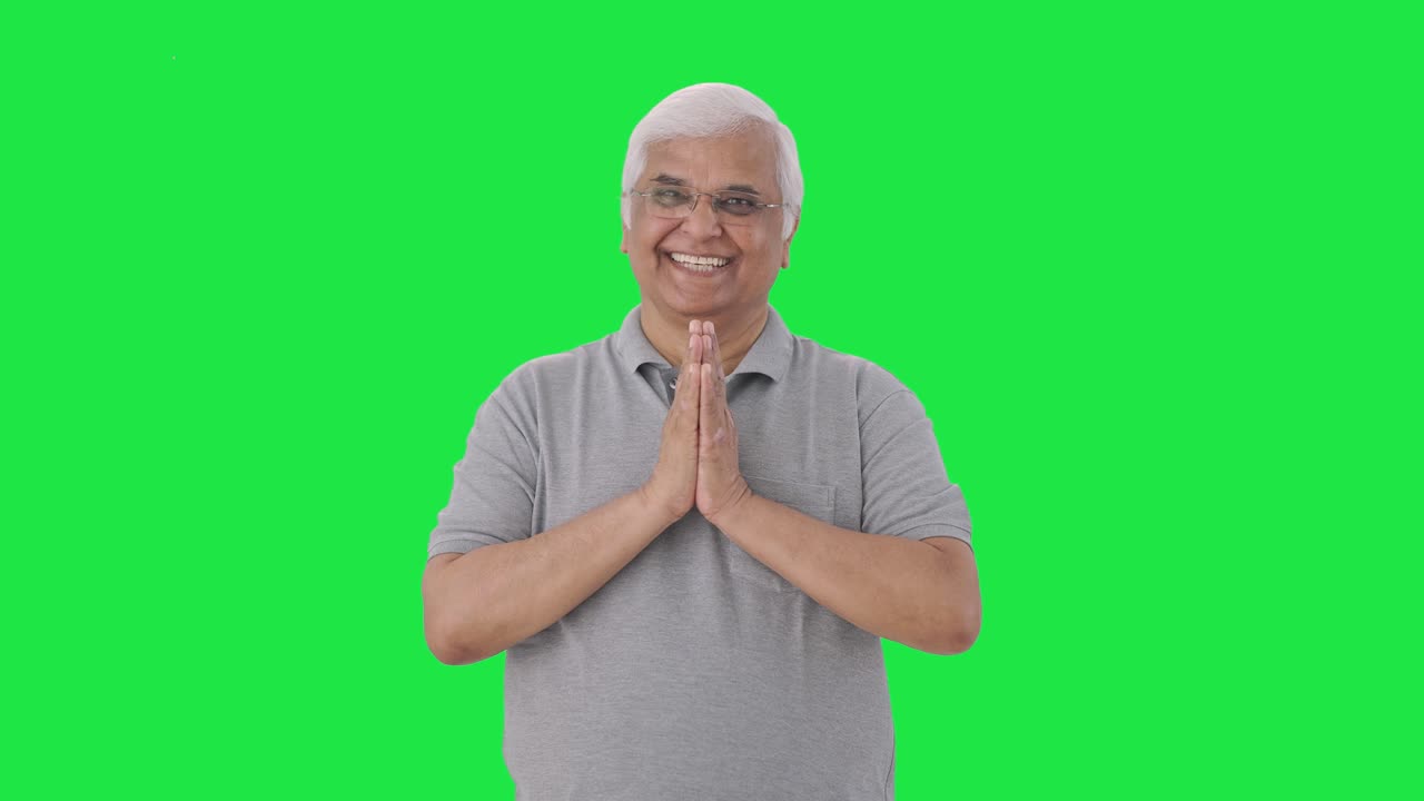 Happy Indian old man doing Namaste and greeting Green screen
