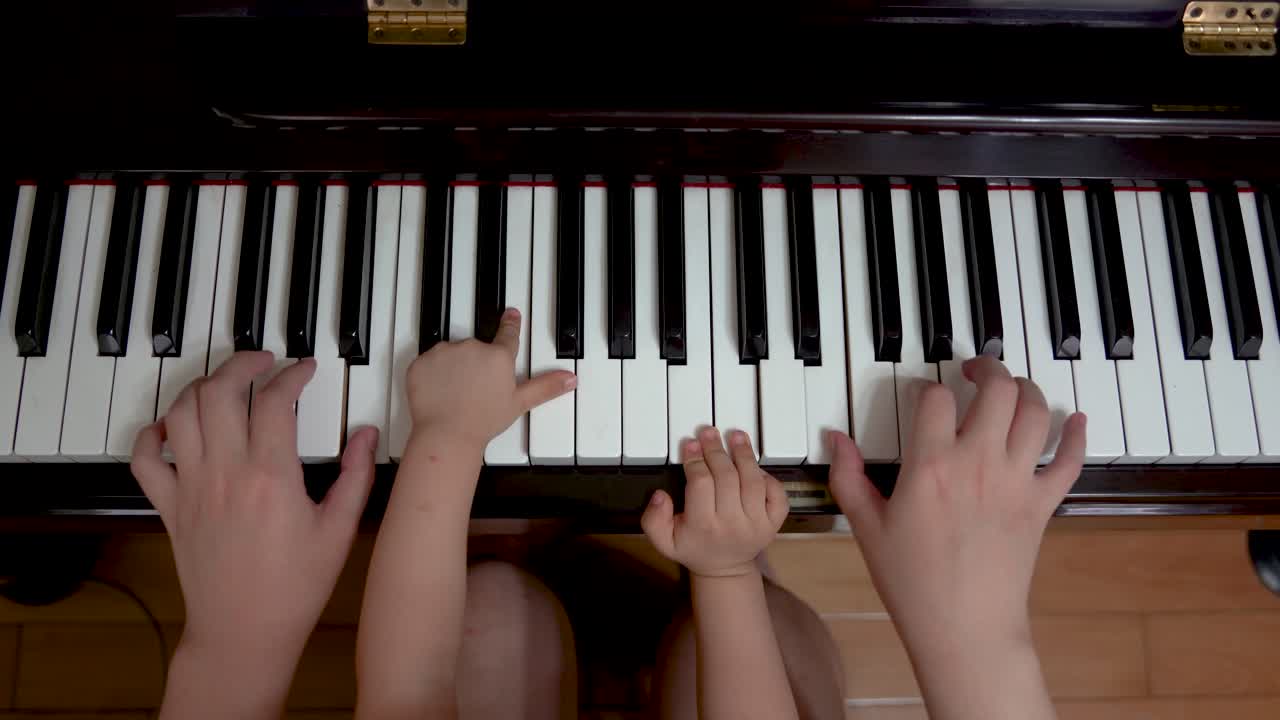 niño tocando el piano con un adulto, cuatro manos, dúo de piano.