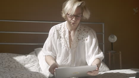 adult woman does office work on bed at home, tilt, medium