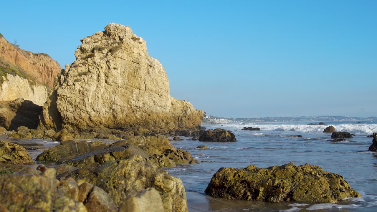 las olas se estrellan en cámara lenta en la orilla de la playa de el matador en la hora dorada en malibú, california.