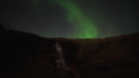 fascinante aurora boreal por la noche sobre una cascada en el país escandinavo