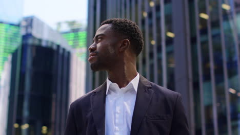 Portrait-Of-Confident-Young-Businessman-Wearing-Suit-Standing-Outside-Looking-Up-At-Offices-In-The-Financial-District-Of-The-City-Of-London-UK