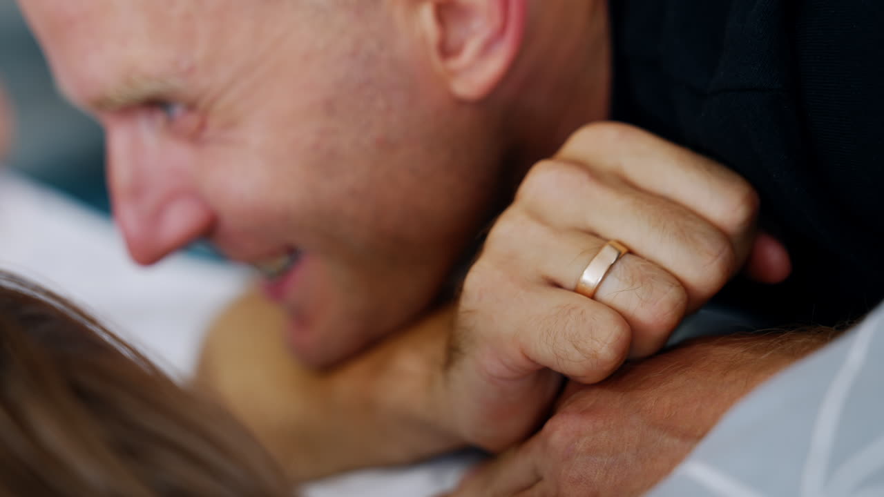 Face of a happy smiling man looking and talking to his newborn baby. Childbirth in the hospital.