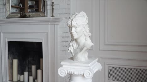 white marble bust of a woman in a white room with fireplace