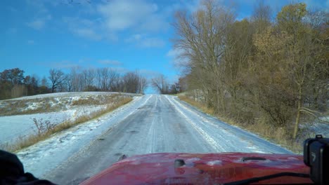 Driver-POV-while-driving-a-snowy-country-road-past-corn-fields-on-a-sunny-late-autumn-afternoon