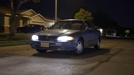 nighttime drive through suburban streets: a blue sedan navigates quiet roads while illuminated headlights cut through the darkness