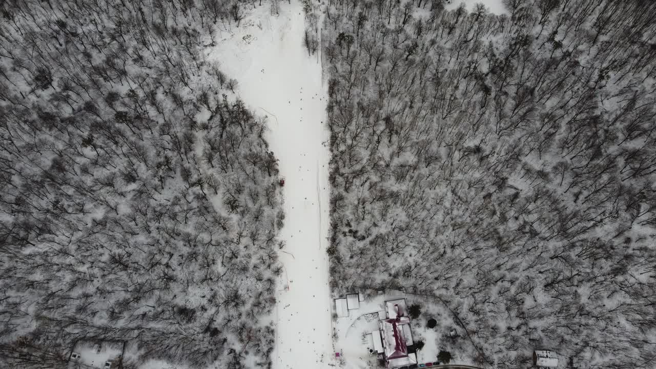 주말에 스키 리프트를 이용해 눈 슬로프에서 스키를 타는 스키어와 스노보더. 서리가 내린 겨울날 스키 리조트에서 스키어와 스노보더들과 함께 눈 덮인 슬로프 위로 날아가는 드론:드론 보기