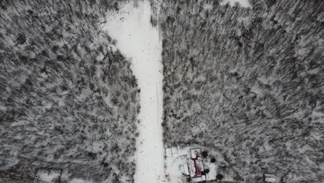 Skiers-and-snowboarders-skiing-on-snow-slopes-with-ski-lift-at-weekend.-Drone-flying-over-snowy-Slope-with-Skiers-and-Snowboarders-at-Ski-Resort-on-a-frosty-winter-day:-drone-view