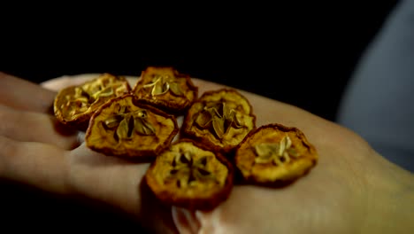 close-up of fingers move a handful of dry apple in hand on a black background.