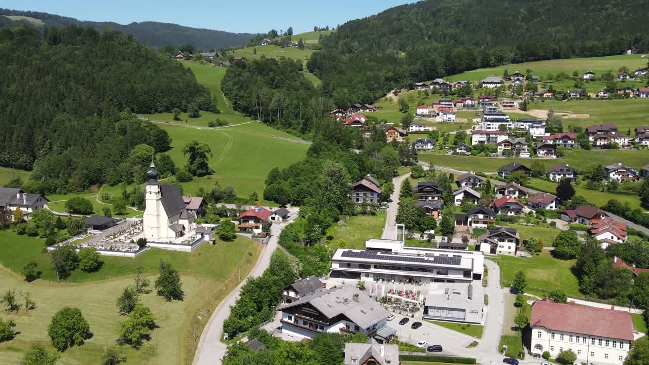 Der Attersee in Österreich, ein beliebtes Touristenziel in der alpinen Region Salzkammergut. Luftaufnahme eines Alpendorfes mit Kirche, grünen Hügeln und umliegender Landschaft