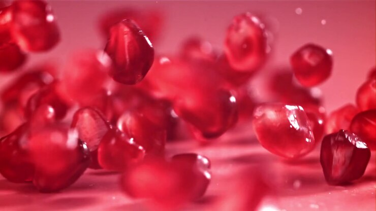 Red Pomegranate Seeds Falling in Slow Motion on a Pink Background