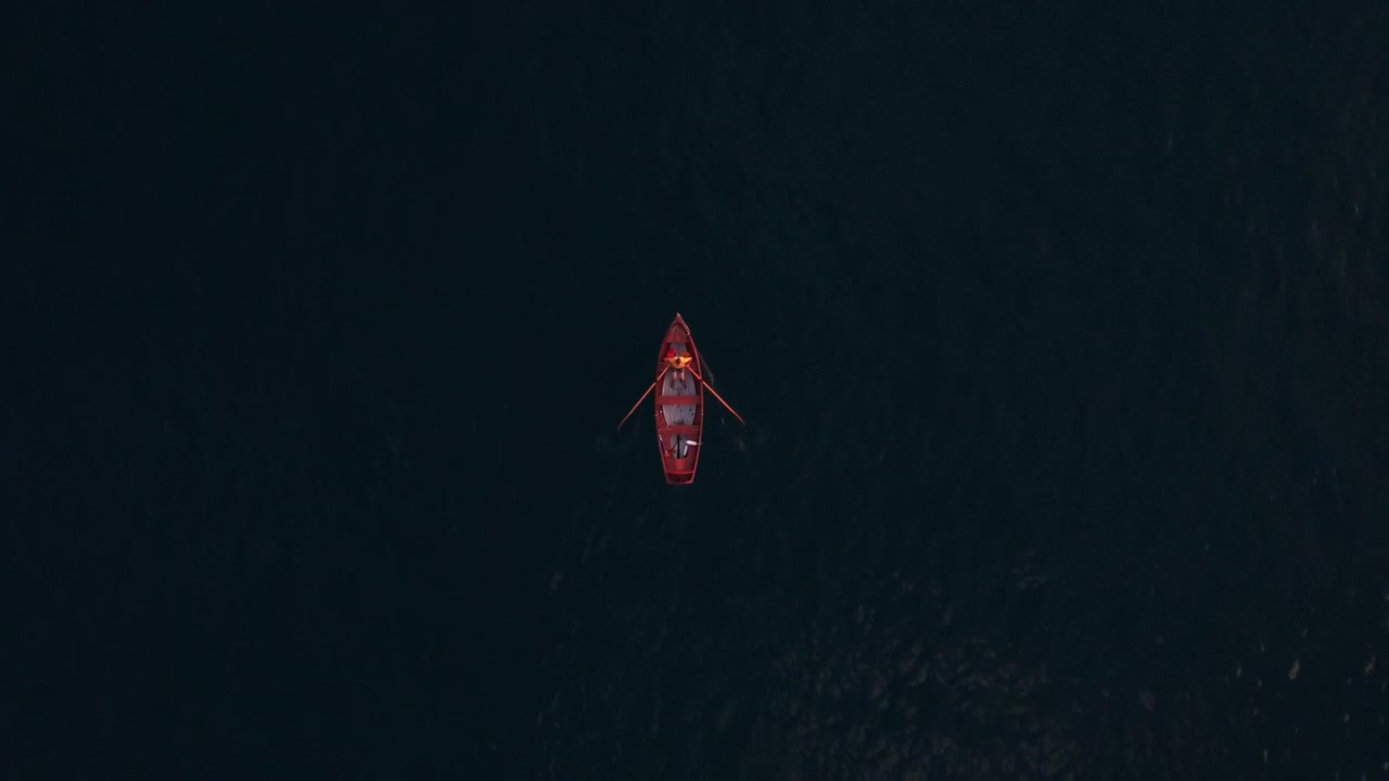 Top down view of a red paddling boat in a deep dark blue lake