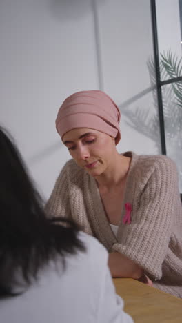 vertical video of anxious young woman patient wearing headscarf undergoing chemotherapy treatment for breast cancer meeting with oncologist or doctor in hospital 1