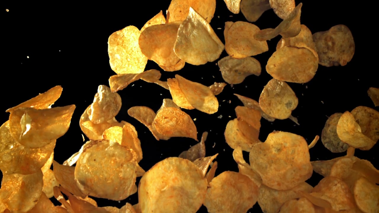 Crispy Golden Potato Chips Falling in Slow Motion on Black Background