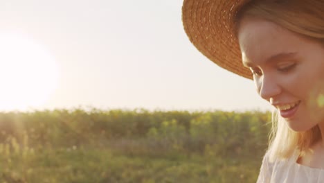 woman wearing hat in a field of sunflowers making a photo