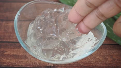close-up of hand touching aloe vera gel in a glass bowl