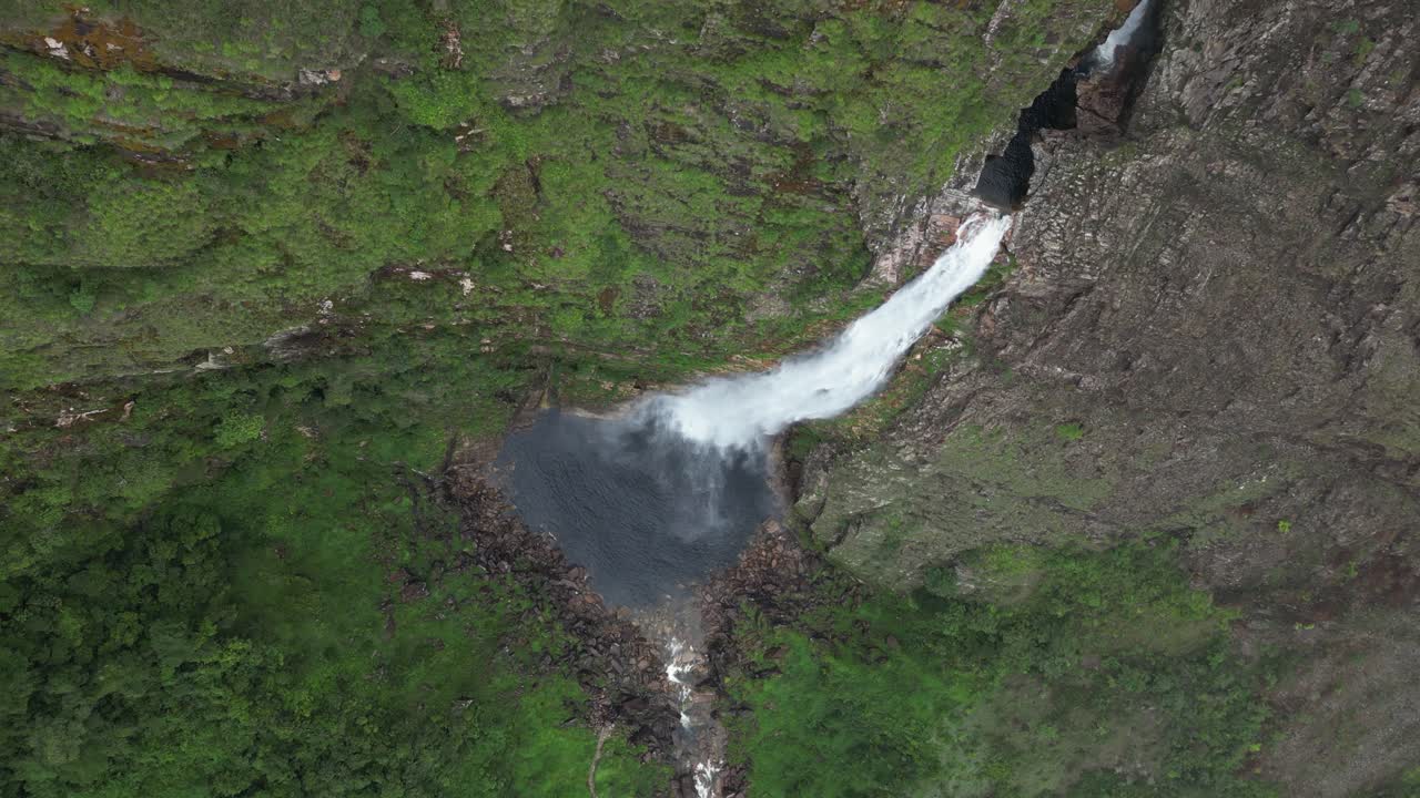 Vertical format: Flyover dramatic tall waterfall through passing cloud