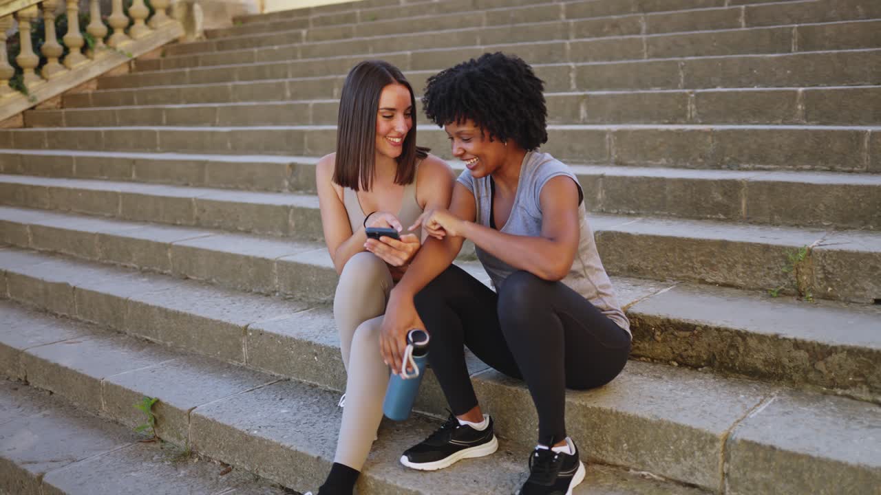 Mulheres Diversas Felizes Compartilhando Conteúdo do Smartphone em Degraus ao Ar Livre