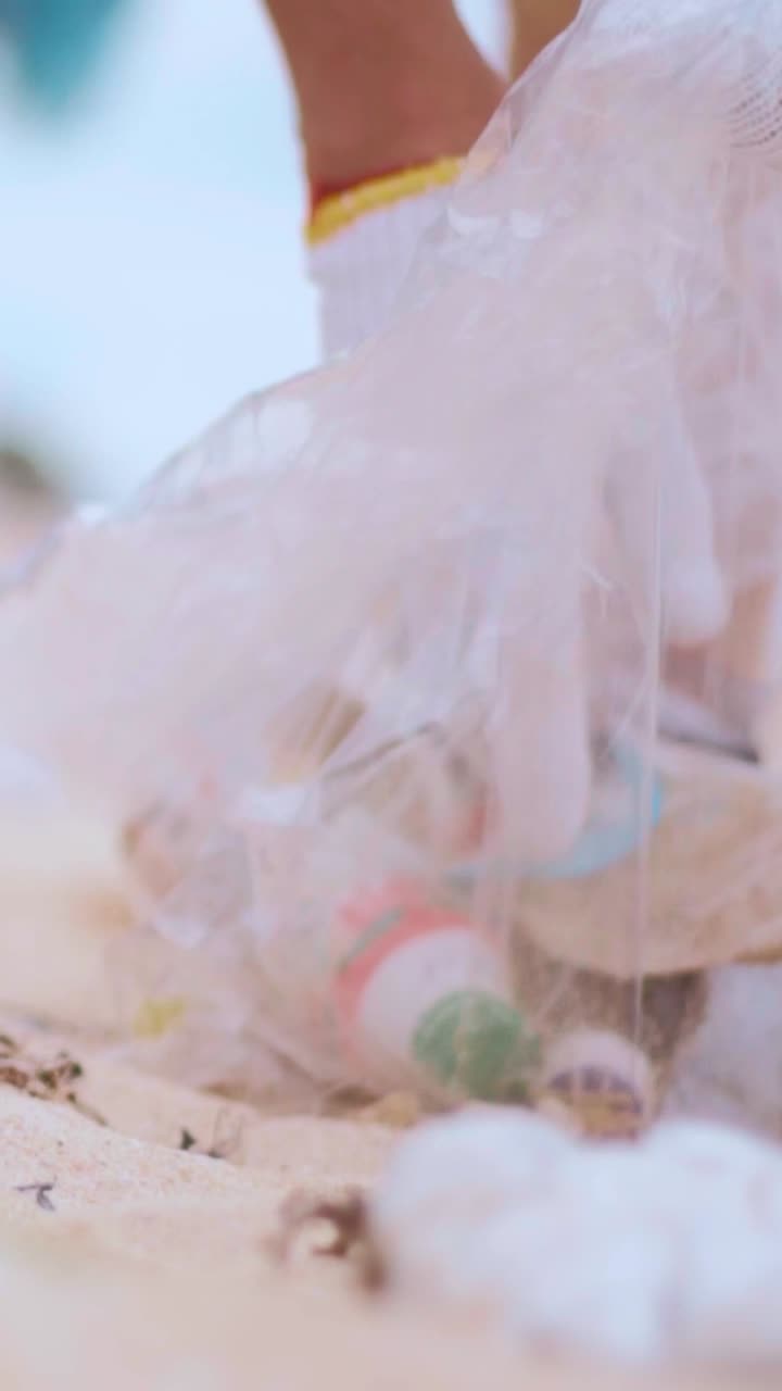 Hands of eco activist collecting waste from sandy beach to save planet