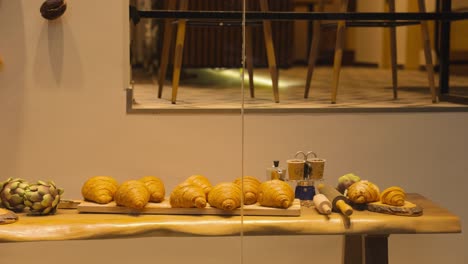 A-close-up-view-of-a-bakery-display-window-showcasing-an-assortment-of-freshly-baked-bread-and-pastries