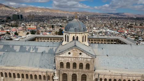 beautiful aerial view over the umayyad mosque in syria. drone is flying over the mosque with the city of damascus in the background.