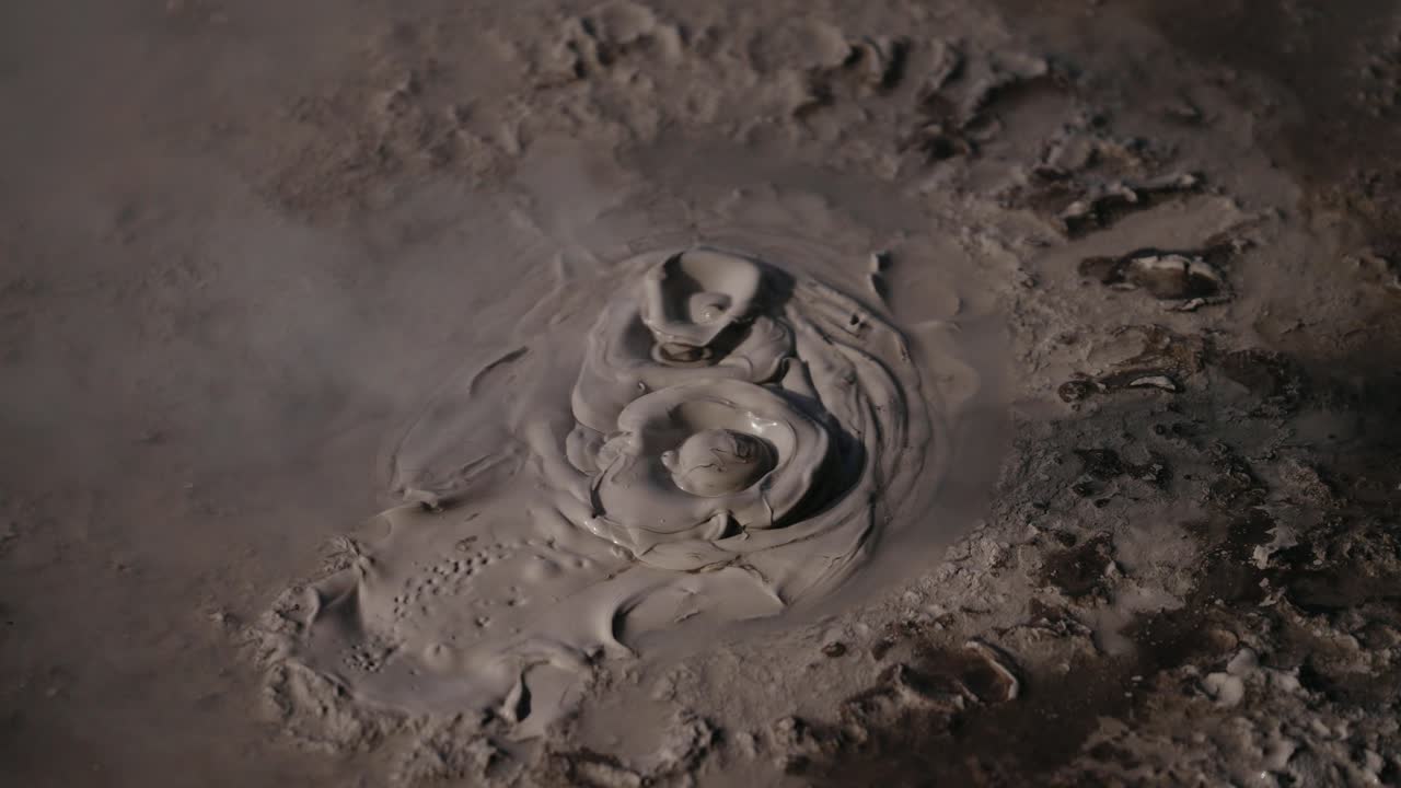 Primo piano di una pozza di fango vulcanico geotermico bollente, con lago fumante, fango ribollente e vapore, un'immagine soddisfacente.