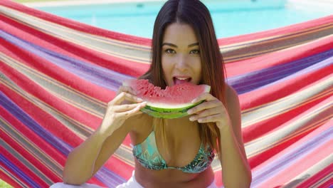 una mujer joven y bonita sosteniendo una sandía comida.