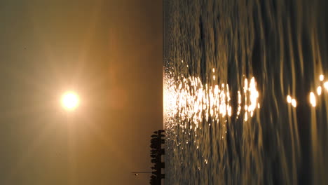 people on pier in distance at sunset