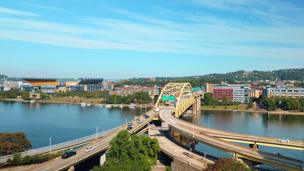 Flow of cars moving on the Fort Duquesne Bridge over the Allegheny River in Pittsburgh, Pennsylvania. Drone footage over the cityscape distancing from the bridge