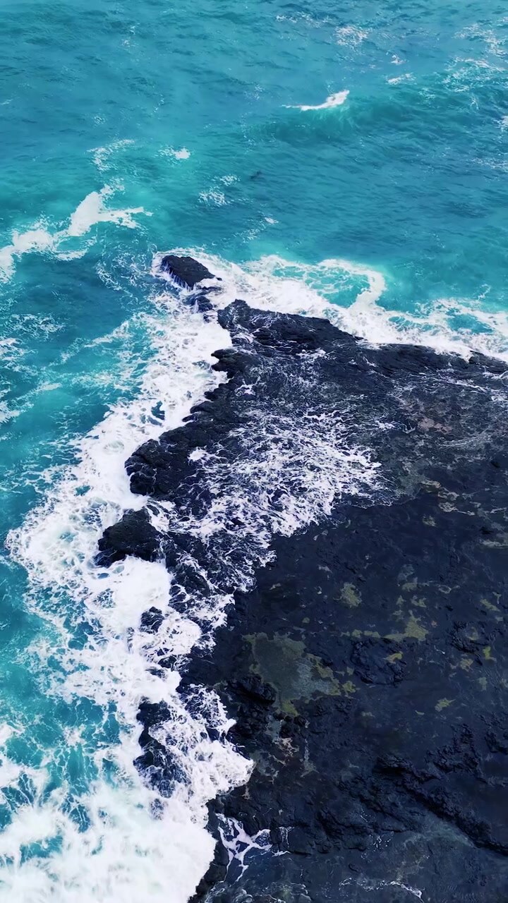 Ripresa aerea dall'alto di onde turchesi che si infrangono contro rocce costiere scure a Flinders, Australia