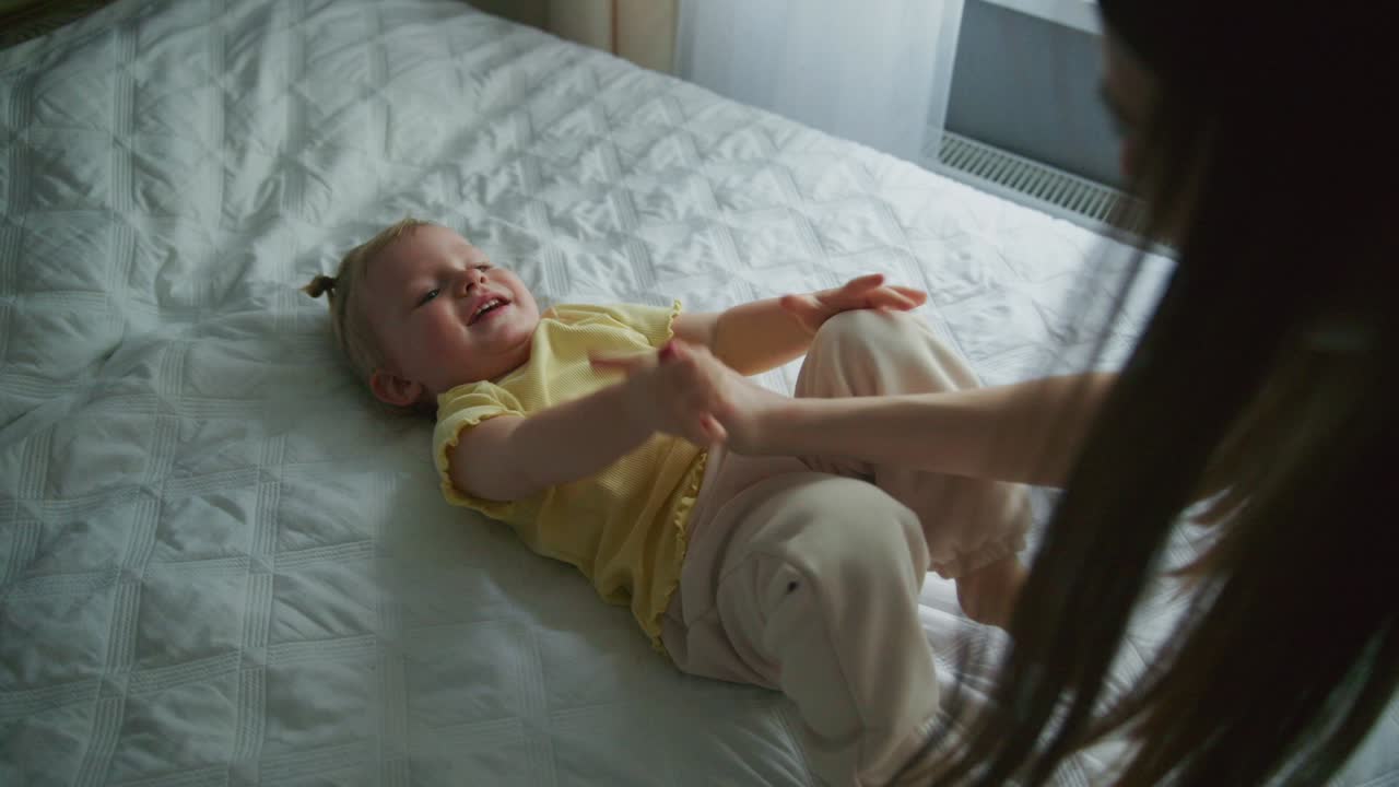 Happy Baby Playing and Laughing on Bed with Parent's Hand