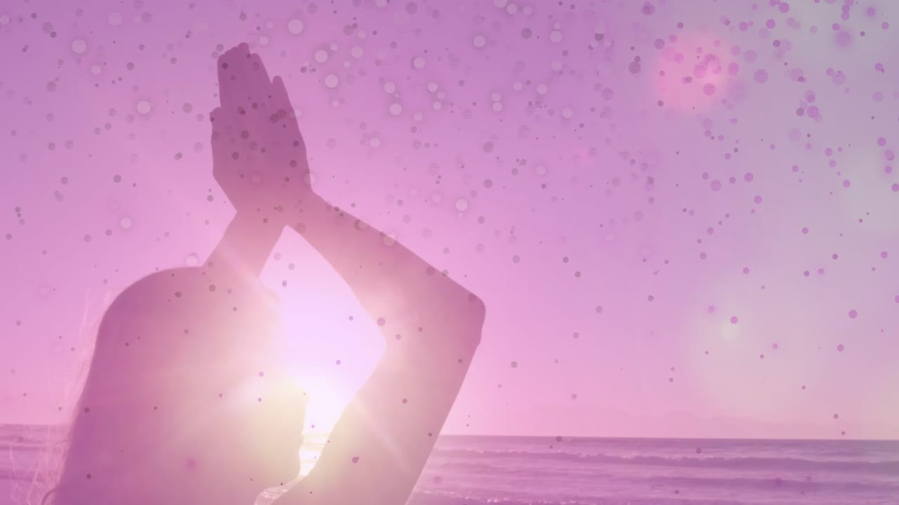 Donna che medita sulla riva, il sole si allinea dietro la testa causando un riflesso della lente e macchioline rosa-violacee.