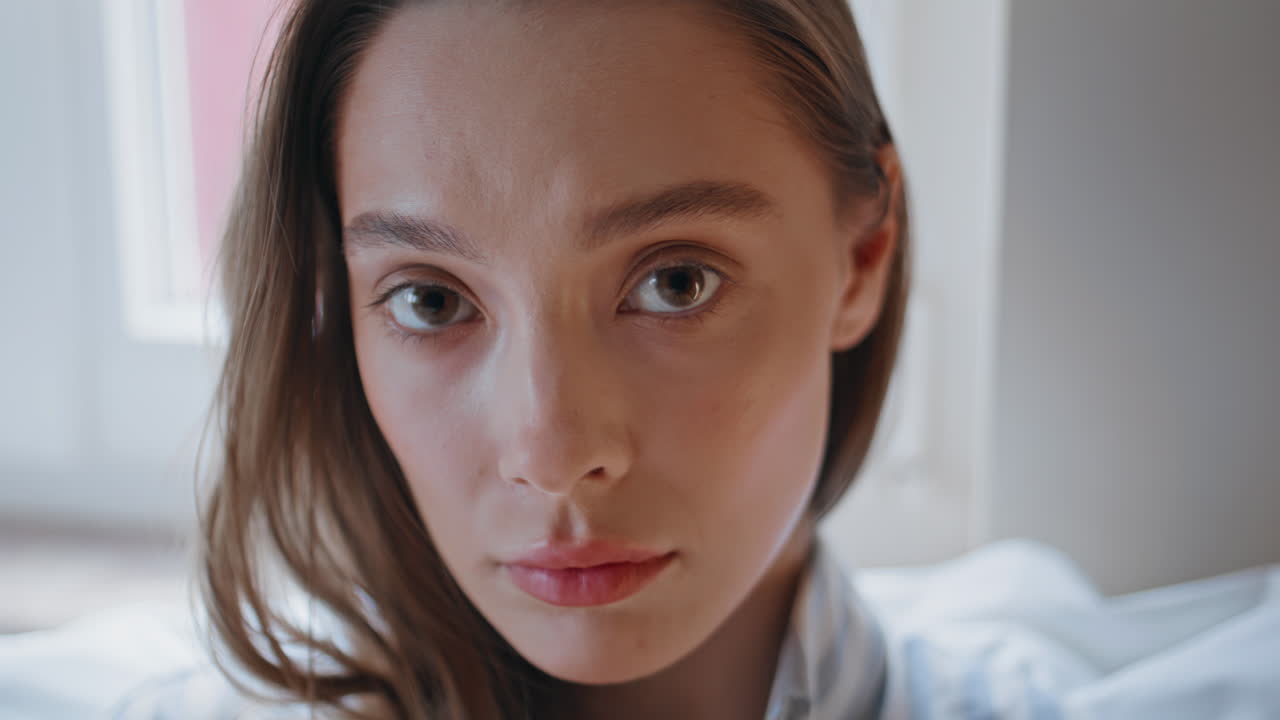 Serious girl looking camera with attentive gaze in white home interior closeup