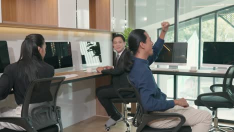 asian business teamwork sitting on chair looking screen of computer with raised hands and having fun celebrate victory